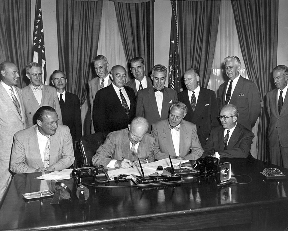 President Eisenhower signs H.R. 9757, an act "to amend the Atomic Energy Act of 1946." The signing was witnessed in his office by various senators, congressmen and members of the Atomic Energy Commission, August 30, 1954. Among the notable people include 
