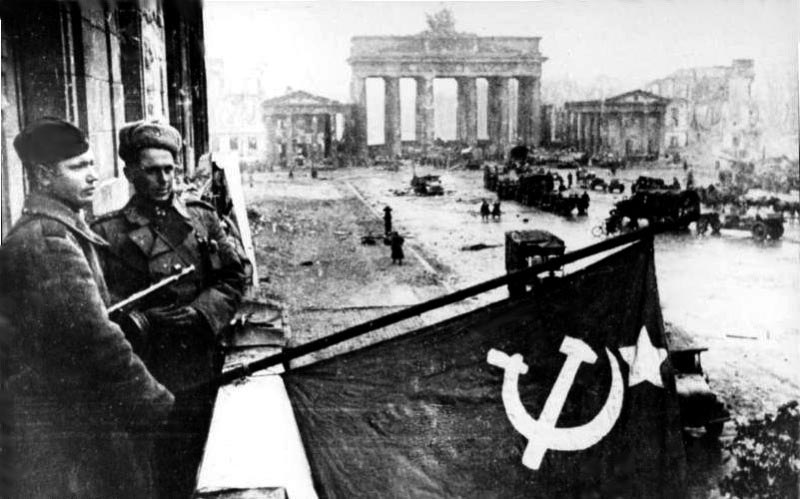 Soviet soldiers hosting the Soviet flag on the balcony of Hotel Adlon in Berlin after the Battle of Berlin.