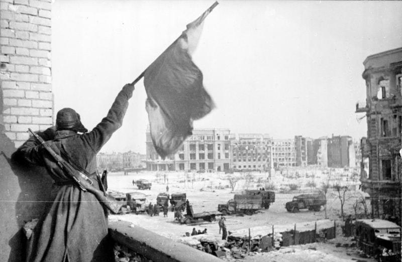 Soviet soldier waving a Red Banner over the central plaza of Stalingrad in 1943.
